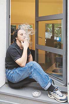 Raucher in einem geöffneten Fensterrahmen sitzend