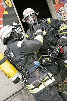 Feuerwehrleute beim Einsatz mit Schutzanzug und -maske