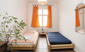 Zimmer einer Ferienwohnung mit Betten, Nachttischchen und Schreibtisch