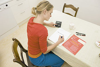 Eine Mieterin sitzt am Küchentisch vor einem Schreibblock