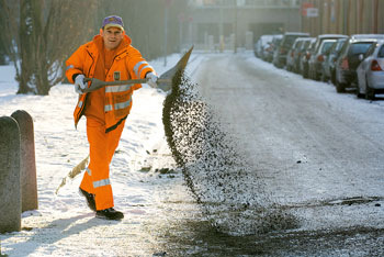 BSR-Mitarbeiter verteilt Streugut auf verschneiter Straße