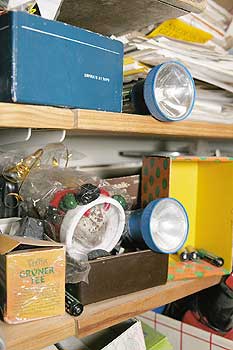 Lampen, Kisten, Zeitungen - gestapelt in einem Regal