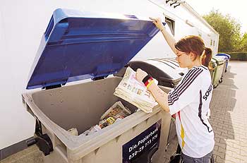 Frau beim Einwurf von Altpapier in einen Papier-Sammel-Behälter