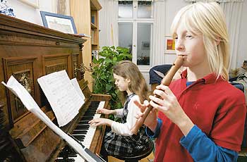 Zwei Jugendliche spielen in einer Mietwohnung Klavier und Blockflöte