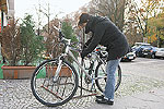 Ein Fahrrad wird auf der Straße an einen Fahrradständer angeschlossen