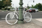 Weiß gestrichenes Fahrrad an einem Laternenpfahl