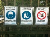 Drei Schilder 'Vorsicht Baustelle' an einem Gartenzaun
