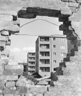 Blick durch ein Mauerloch auf Wohngebäude Blick durch ein Mauerloch auf Wohngebäude