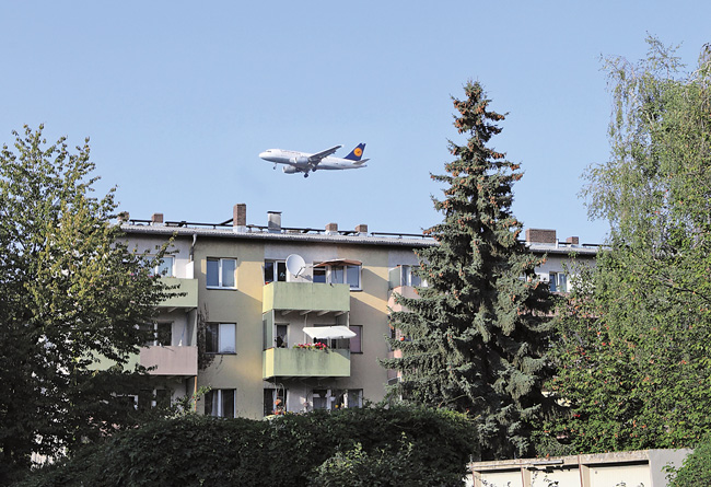 Flugzeug über Wohnbebauung im Landeanflug