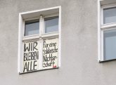 Protestplakat im Fenster: Wir bleiben alle
