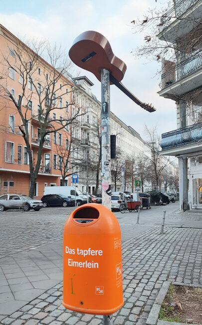 Gitarre, die auf einem Straßenschild steckt